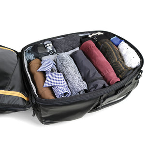 Black travel bag with neatly folded clothes on a white background