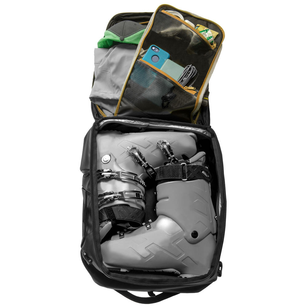 Open backpack with gray ski boots and green jacket on a white background
