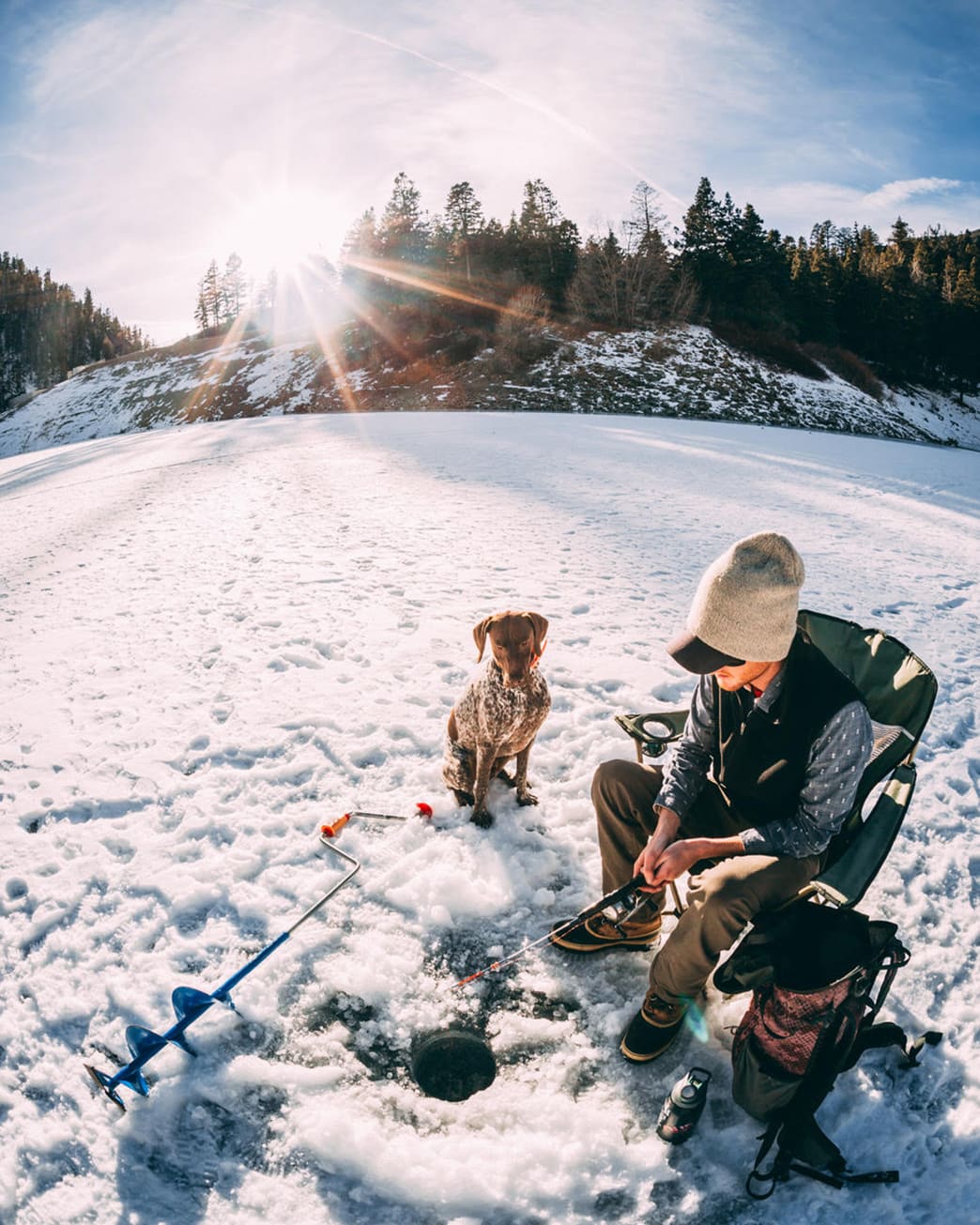 Man ice fishing with his dog