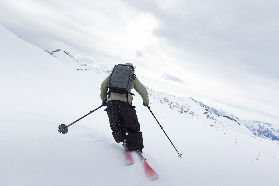 Man skiing in snow wearing kulkea kayda travel backpack