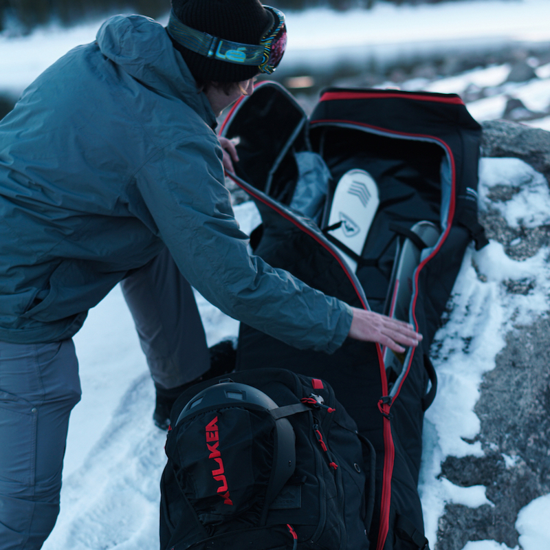 Man packing skis and other gear into kulkea ski bag