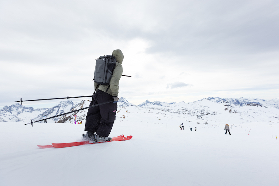Man skiing on snowwy mountain while wearing kulkea travel backpack