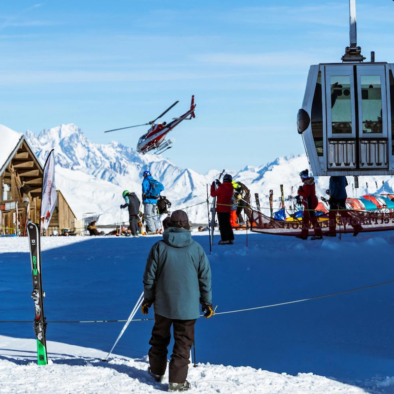 Ski mountain in French Alps with helicopter flying above people