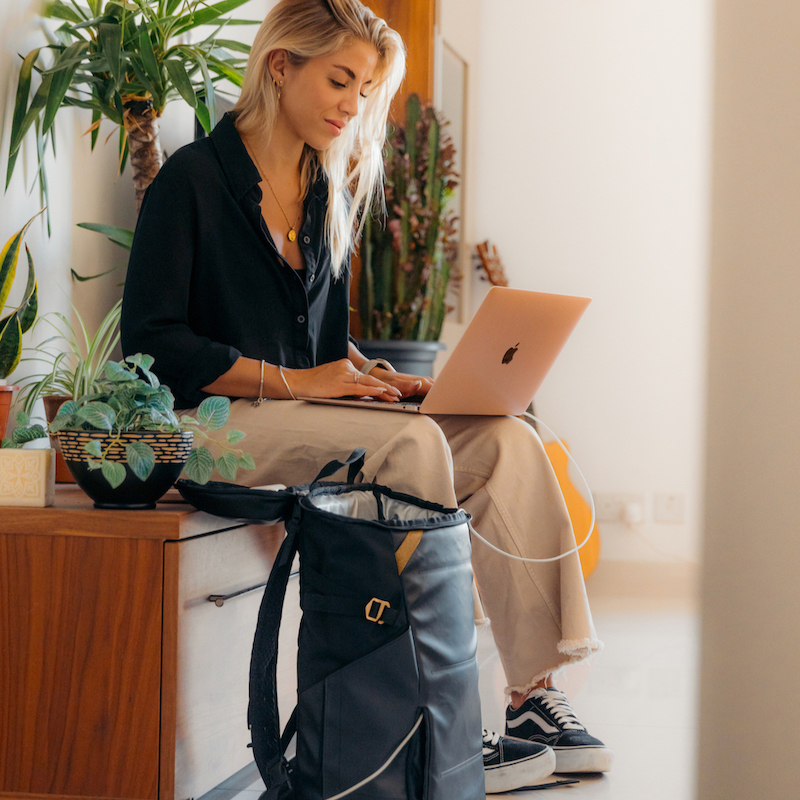 Woman working on laptop with kulkea elaa backpack beside her