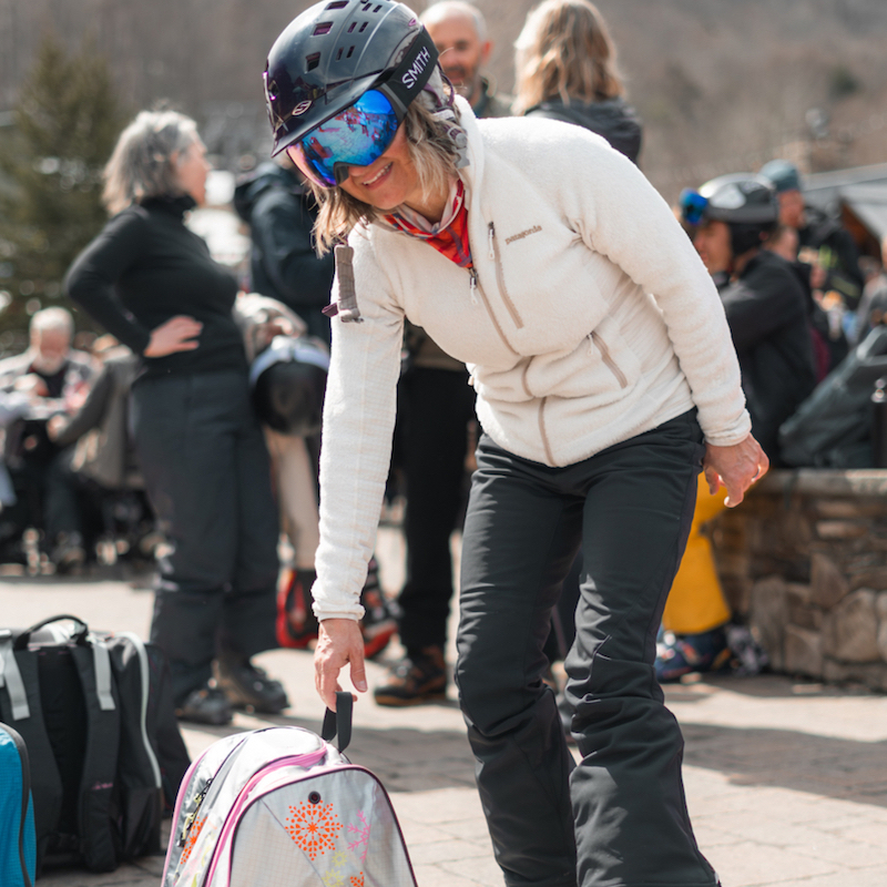 Woman standing at base of ski mountain with kulkea ski boot bag