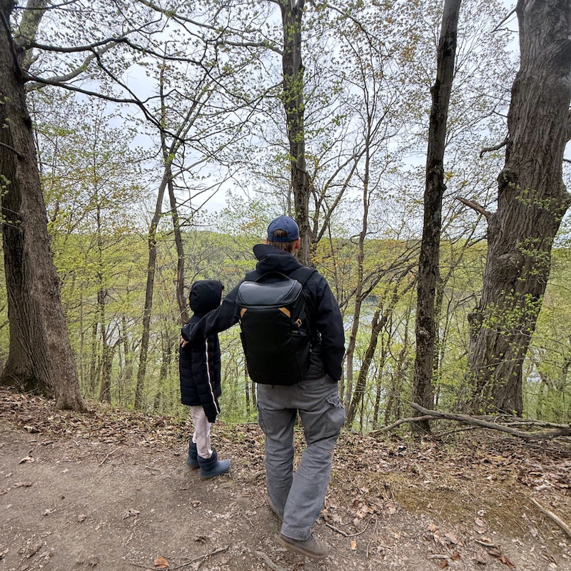 Father and child walking through the woods wearing kulkea kayda travel backpack