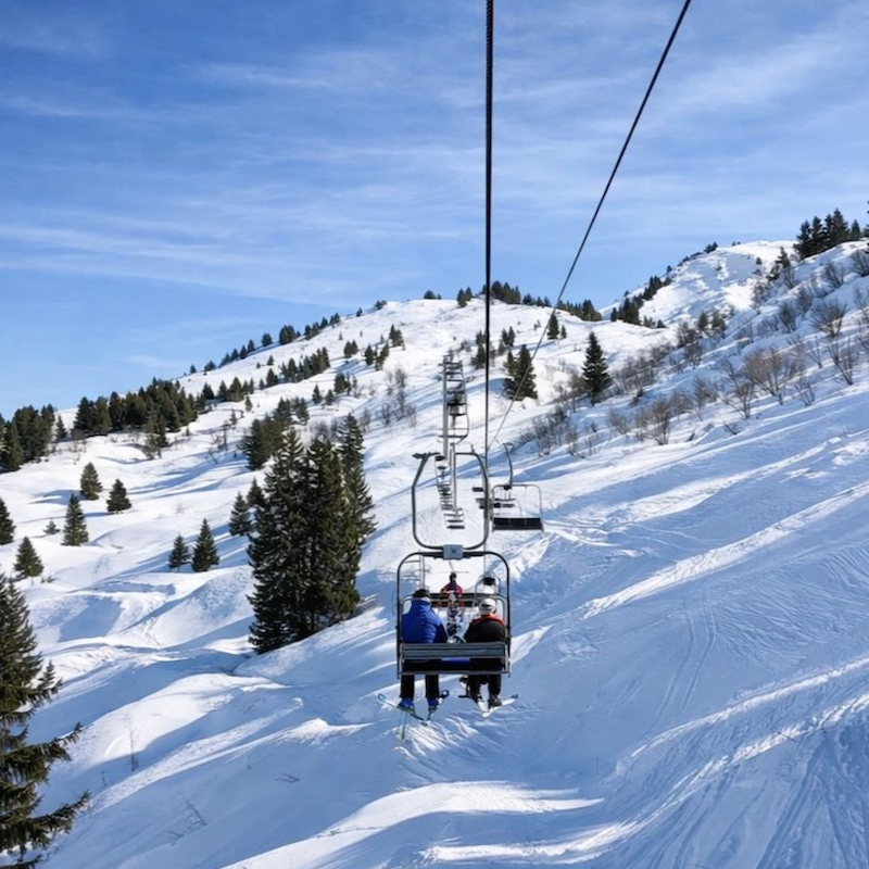 Skiers on chairlift going up mountain